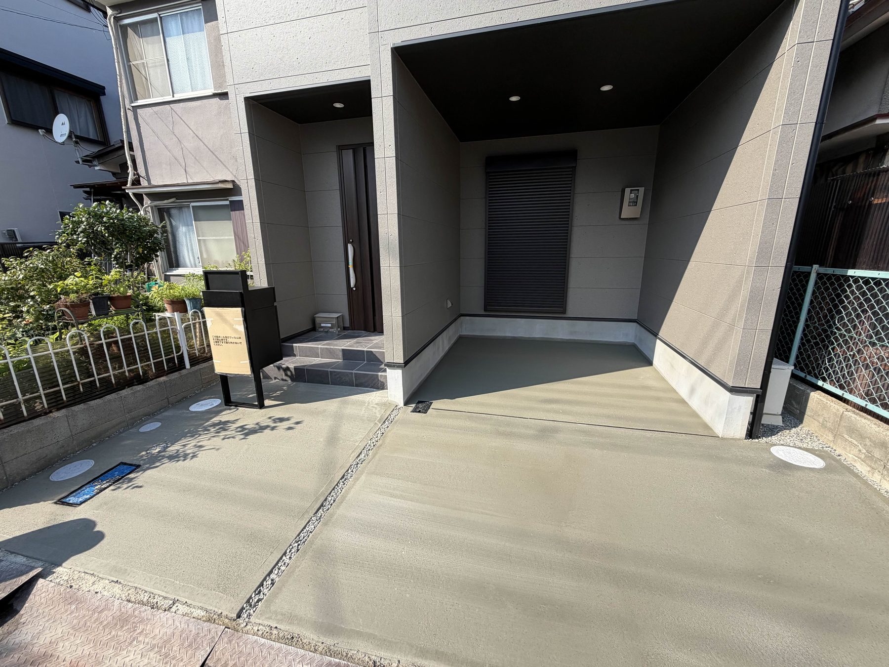 住宅の前面を土間コンクリートで仕上げた駐車場。玄関脇に機能門柱